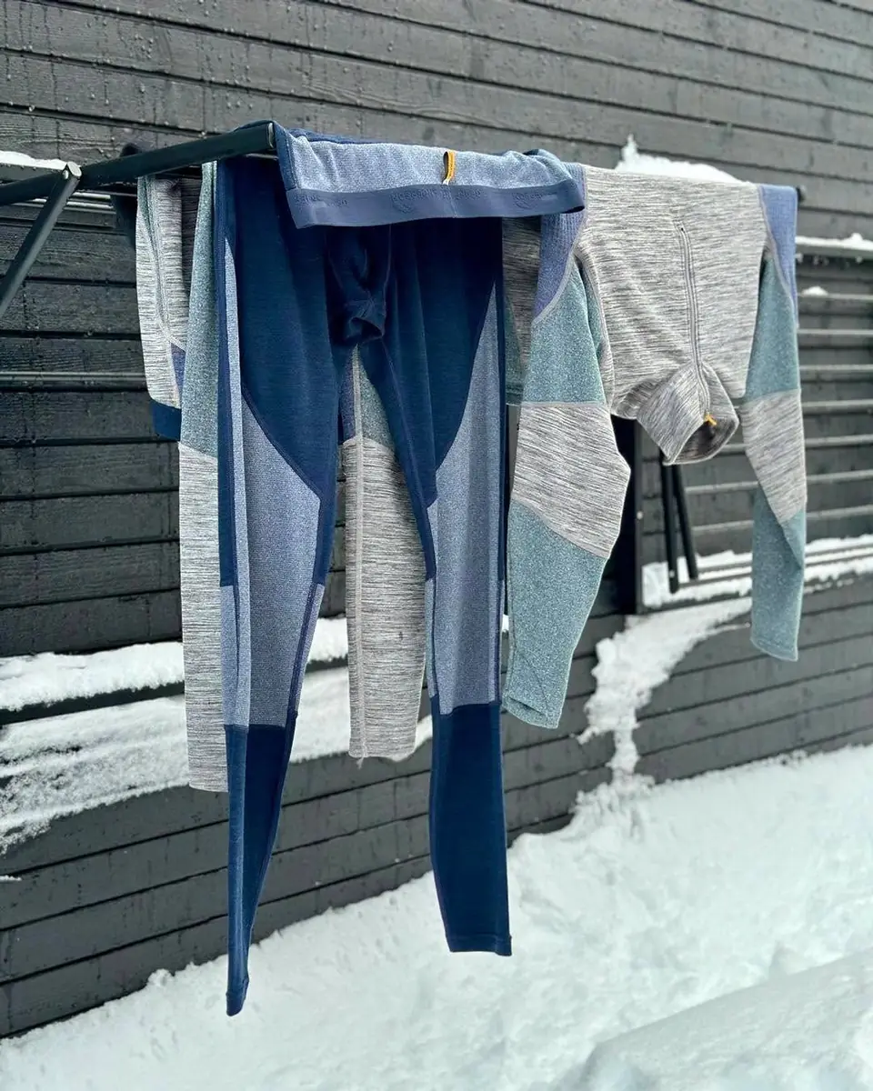 Komplet bielizny termoaktywnej, legginsy i koszulka z długim rękawem, schnący na suszarce przy drewnianej ścianie zimą