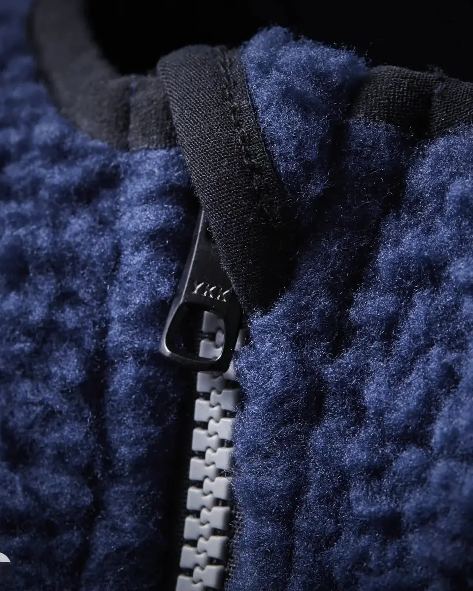 Zbliżenie na granatowy polar z gęstym runem i zamkiem błyskawicznym pod szyją